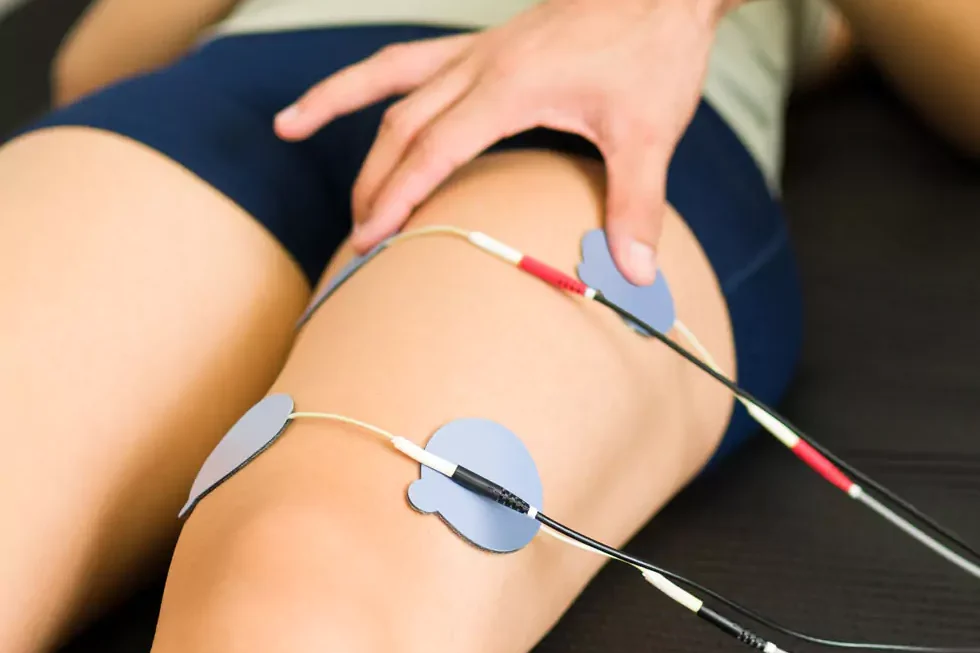 Elektrotherapie Nahaufnahme einer jungen Frau, die eine Elektrotherapie zur Stimulation der Nerven und Muskeln ihres Beins erhält