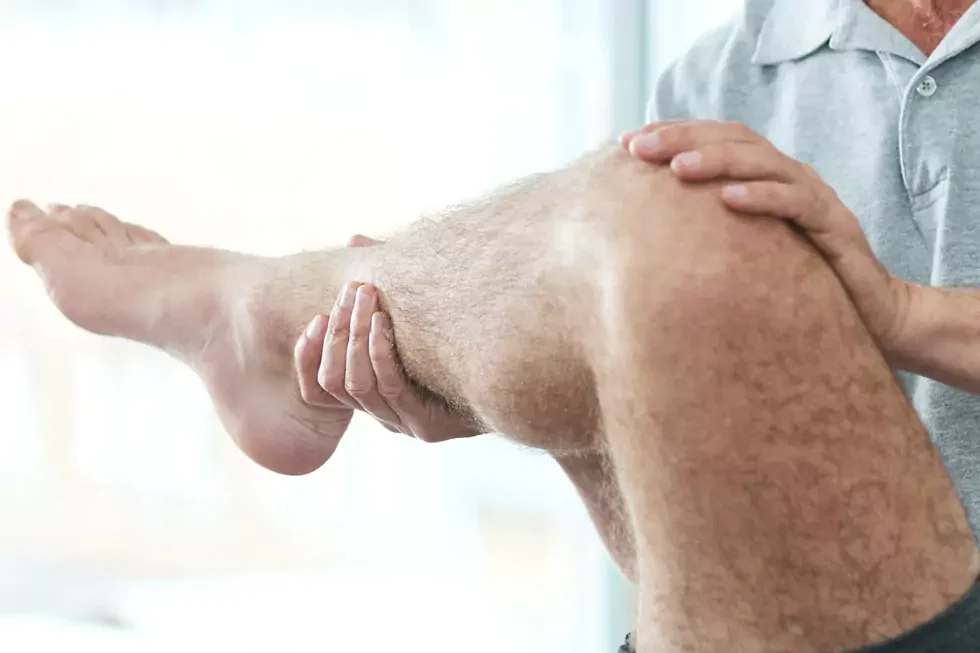 Physiotherapeut behandelt das Knie eines Patienten