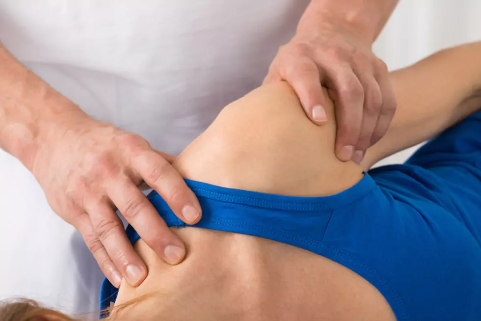Nahaufnahme der Schulter einer Patientin, die von einem Therapeuten behandelt wird