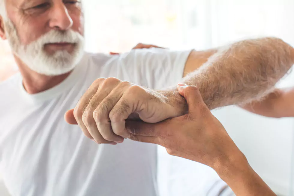 Physiotherapeut untersucht die Beweglichkeit der Schulter eines älteren Patienten